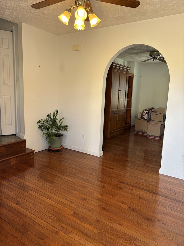spare room with wood-type flooring, arched walkways, ceiling fan, and a textured ceiling