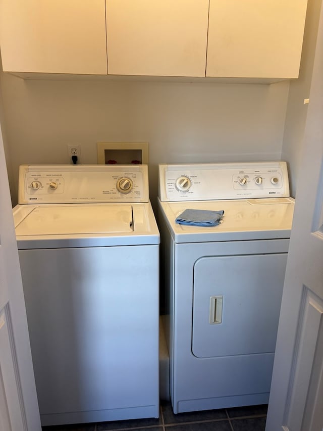 laundry area featuring cabinet space, dark tile patterned flooring, and washer and clothes dryer