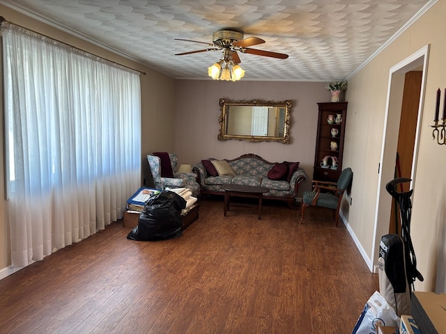 living area with baseboards, ceiling fan, ornamental molding, and wood finished floors