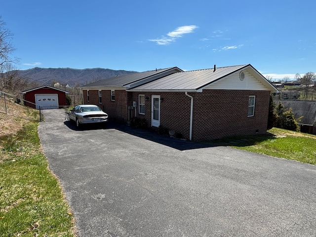 view of front facade featuring brick siding, a garage, a mountain view, an outbuilding, and driveway