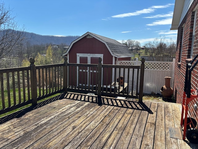 wooden terrace featuring an outdoor structure, a mountain view, and a shed