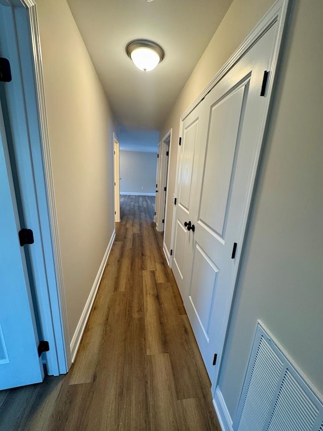 corridor featuring wood finished floors, visible vents, and baseboards