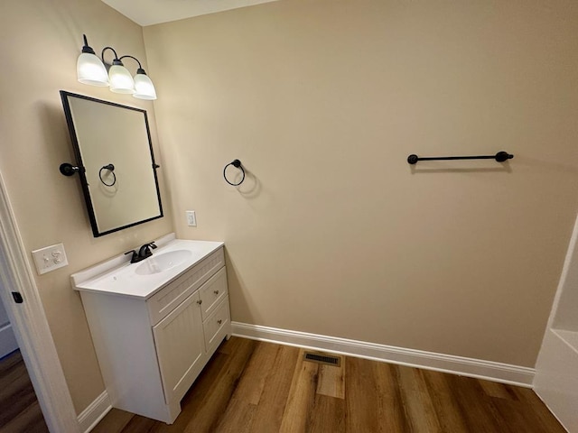 bathroom featuring baseboards, wood finished floors, visible vents, and vanity