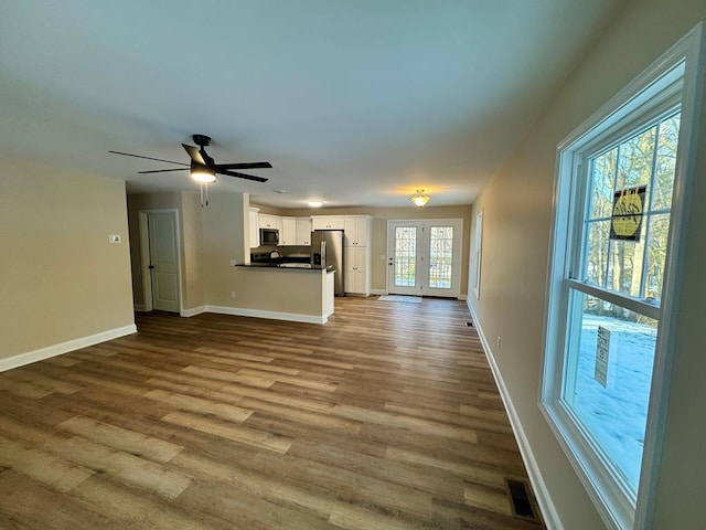 unfurnished living room featuring visible vents, a ceiling fan, baseboards, and dark wood-style floors