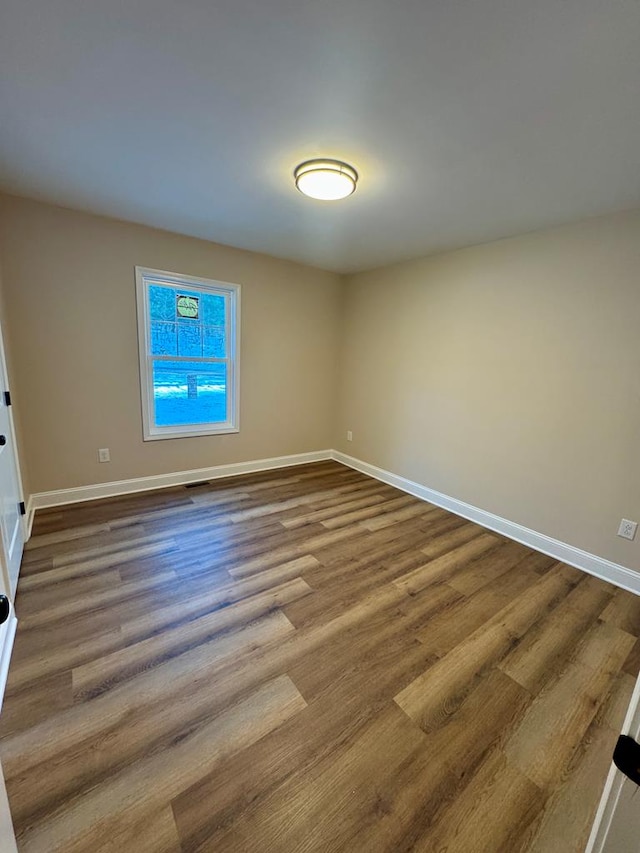 unfurnished room featuring baseboards and dark wood-type flooring