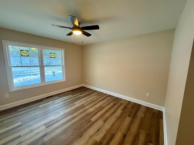 unfurnished room featuring dark wood-type flooring, visible vents, baseboards, and ceiling fan