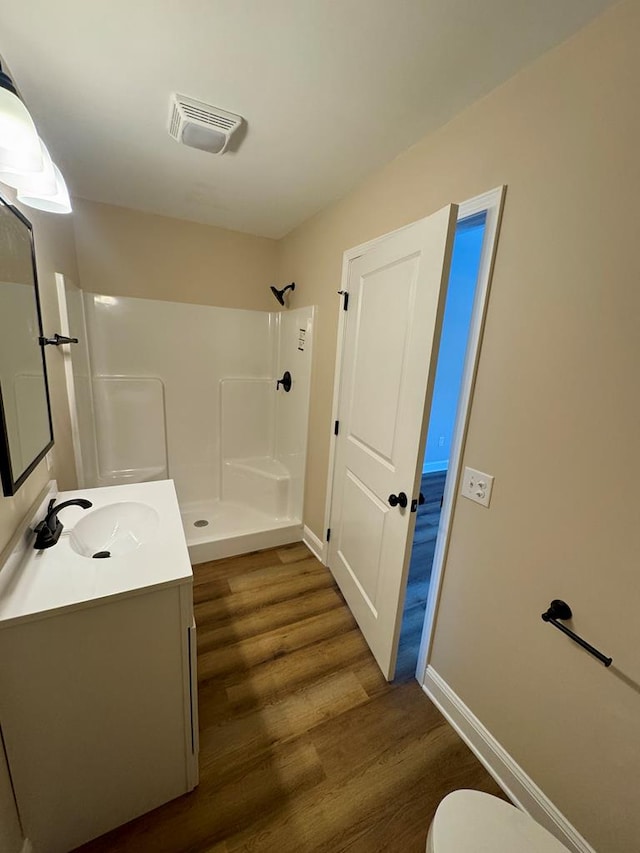 bathroom with vanity, wood finished floors, visible vents, and a shower