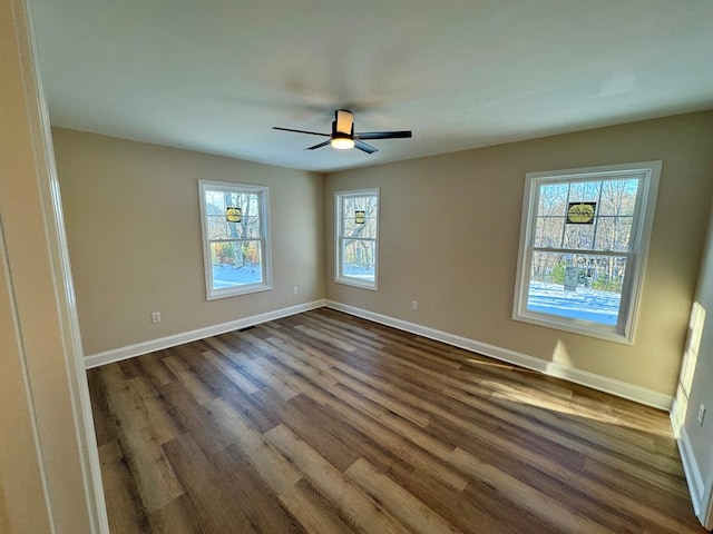 spare room with dark wood finished floors, baseboards, and a ceiling fan