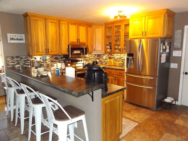 566 Breezy Ridge Rd, Woodlawn, VA 24381 - kitchen featuring stainless steel appliances, a peninsula, dark countertops, tasteful backsplash, and glass insert cabinets
