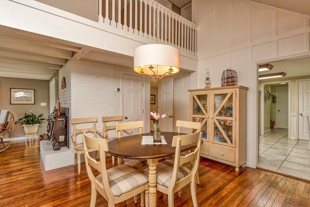 18357 Westwood Dr, Abingdon, VA 24211 - dining space with wood-type flooring, a towering ceiling, a wood stove, and a decorative wall