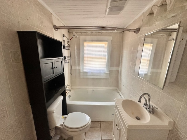 bathroom with toilet, tile patterned floors,  shower combination, vanity, and tile walls