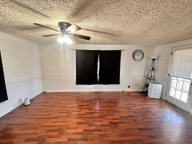 spare room featuring a textured ceiling, wood finished floors, a ceiling fan, and baseboards