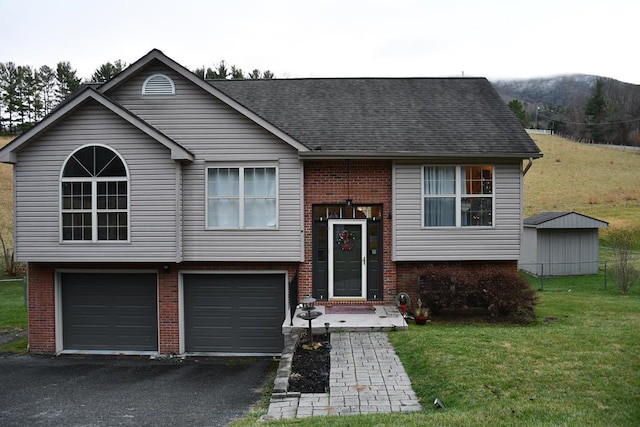 raised ranch featuring an attached garage, brick siding, aphalt driveway, and a front yard