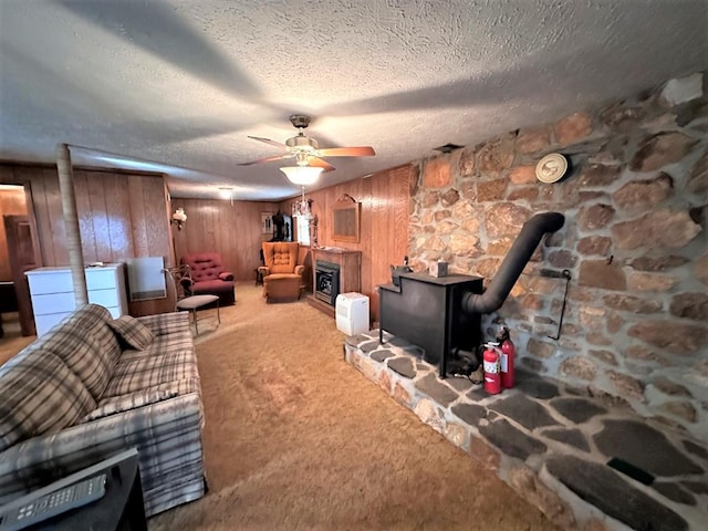542 Volunteer Rd, Fancy Gap, VA 24328 - carpeted living room featuring a wood stove, wood walls, a textured ceiling, and ceiling fan