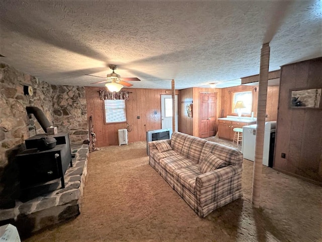 542 Volunteer Rd, Fancy Gap, VA 24328 - carpeted living area with a wood stove, radiator heating unit, wooden walls, ceiling fan, and a textured ceiling