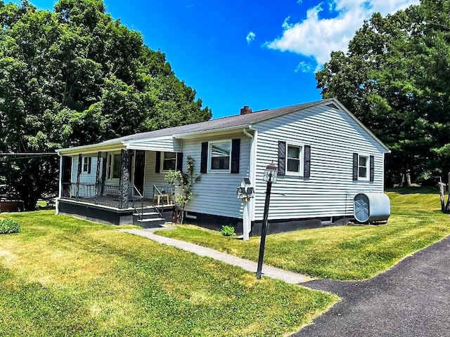 view of front of property featuring heating fuel, a chimney, a porch, and a front lawn