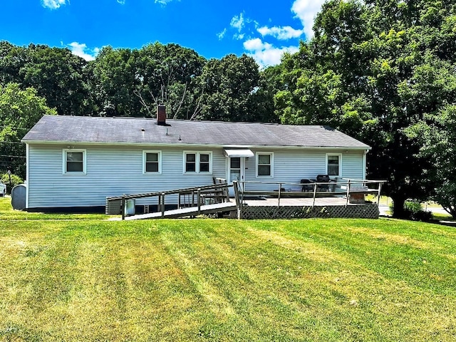 rear view of property featuring a chimney, a lawn, and a wooden deck