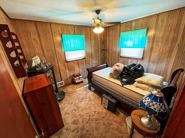 bedroom with visible vents, ceiling fan, wooden walls, and carpet floors