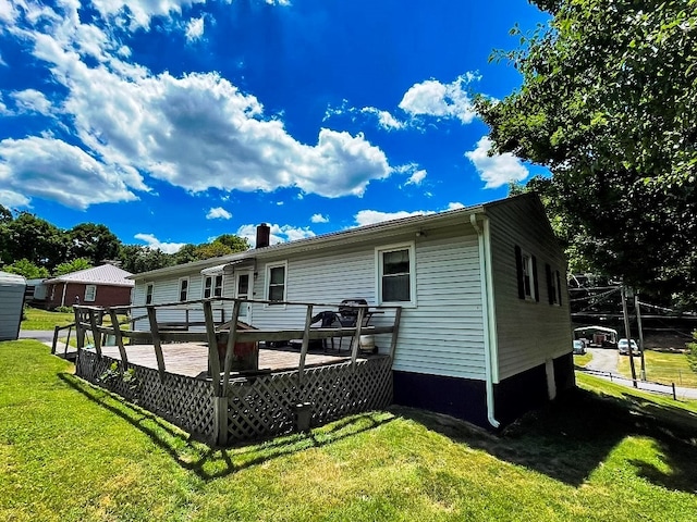 back of house with a lawn, a chimney, and a deck