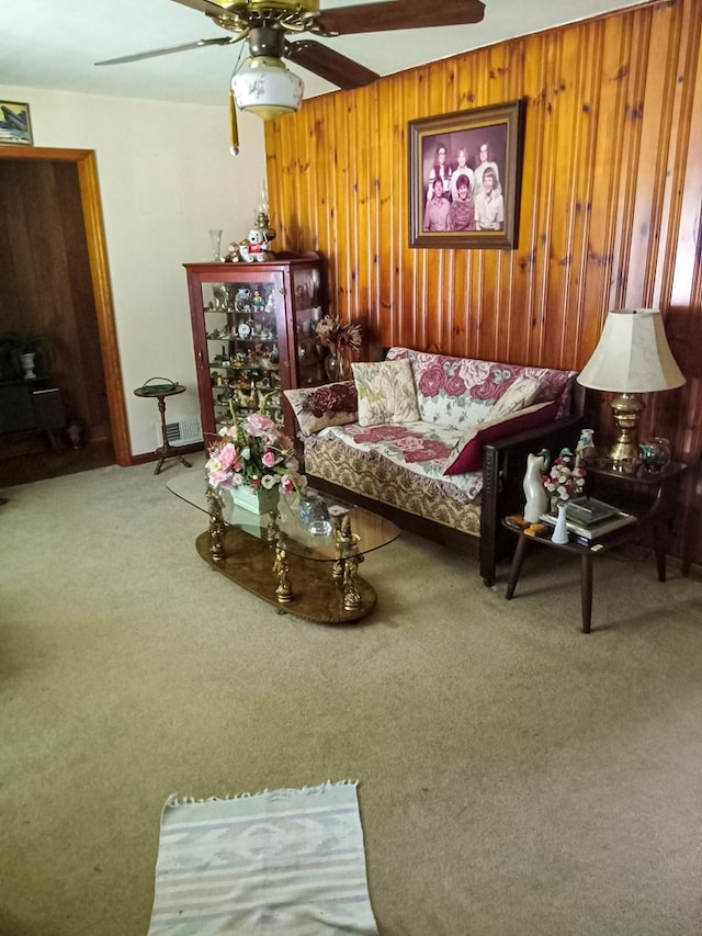 living area with visible vents, wood walls, ceiling fan, and carpet floors