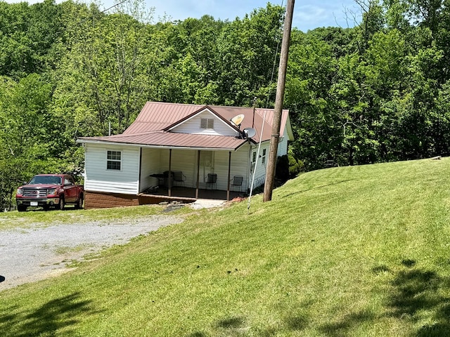 318 Limestone Rd, Pounding Mill, VA 24637 - view of front of house with driveway, a front lawn, a forest view, and metal roof