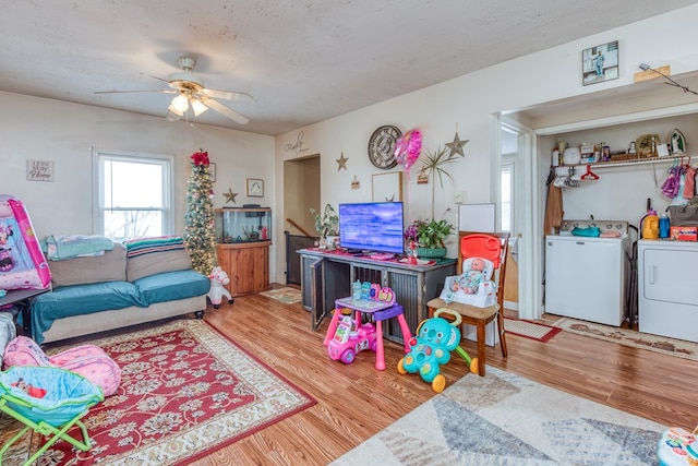 living room with ceiling fan, washer and dryer, hardwood / wood-style floors, and a textured ceiling