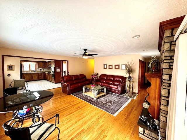 1595 Edgewater Dr, Grundy, VA 24614 - living area with a textured ceiling, light wood-style floors, a ceiling fan, and a fireplace