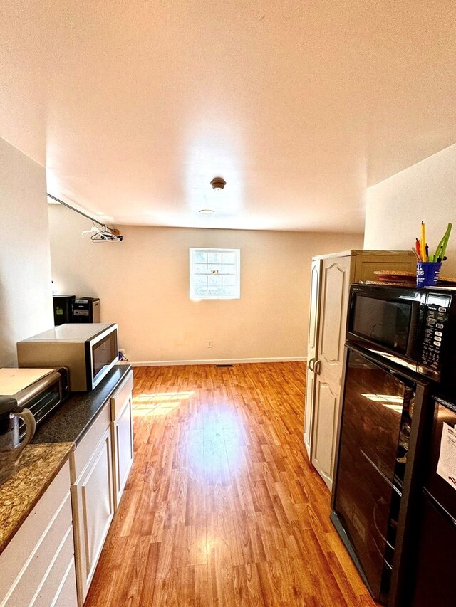 1595 Edgewater Dr, Grundy, VA 24614 - kitchen with light wood-style floors, black microwave, dark countertops, stainless steel microwave, and baseboards