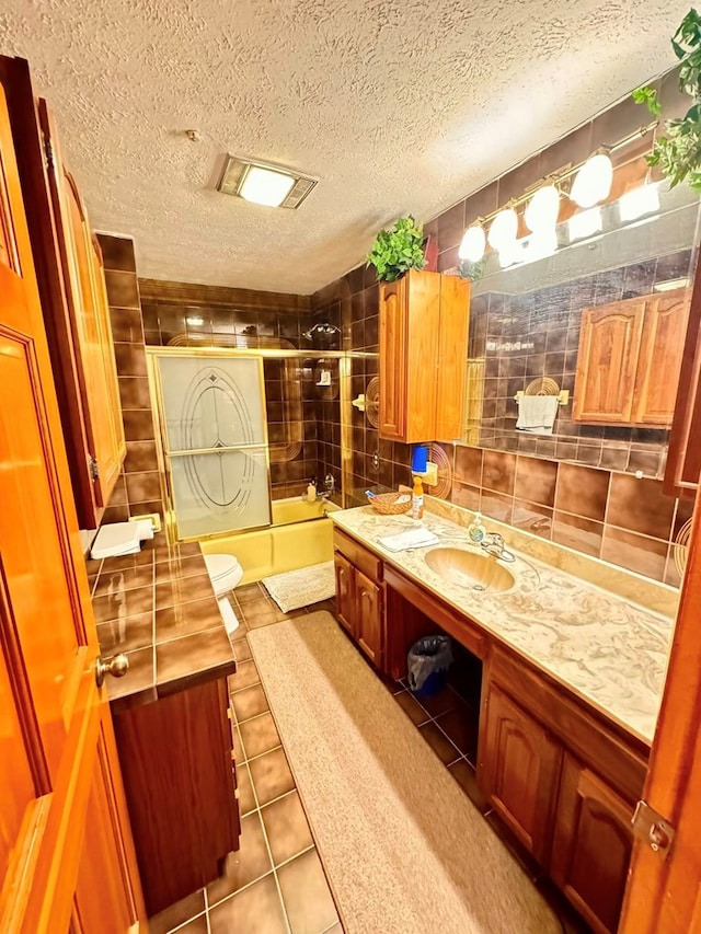 1595 Edgewater Dr, Grundy, VA 24614 - bathroom featuring vanity, combined bath / shower with glass door, tile patterned flooring, a textured ceiling, and toilet