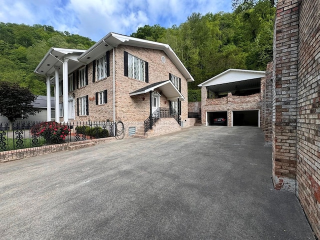 1595 Edgewater Dr, Grundy, VA 24614 - view of side of home with an outbuilding, driveway, brick siding, a garage, and a view of trees