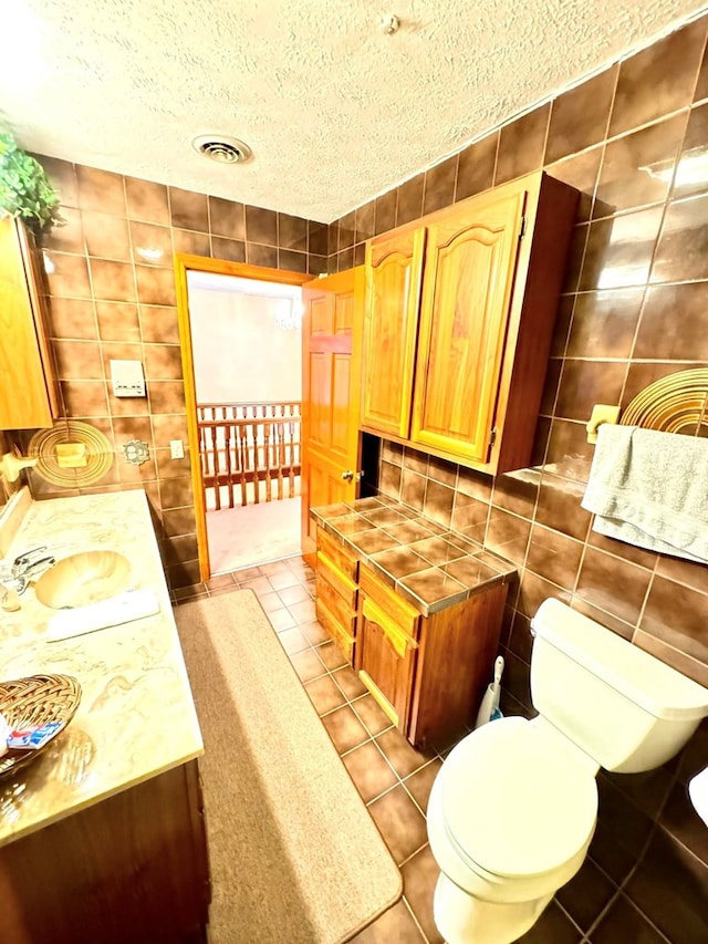 1595 Edgewater Dr, Grundy, VA 24614 - bathroom with tile walls, tile patterned floors, a sink, toilet, and a textured ceiling