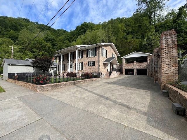 1595 Edgewater Dr, Grundy, VA 24614 - view of front facade with an outdoor structure, a chimney, concrete driveway, fence, and a wooded view
