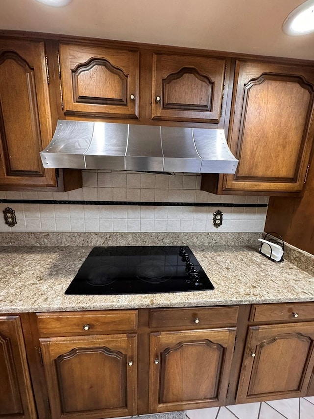 1595 Edgewater Dr, Grundy, VA 24614 - kitchen featuring under cabinet range hood, black electric stovetop, tasteful backsplash, light stone counters, and brown cabinetry