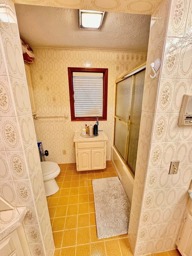 1595 Edgewater Dr, Grundy, VA 24614 - bathroom with wallpapered walls, toilet, bath / shower combo with glass door, a textured ceiling, and tile patterned flooring