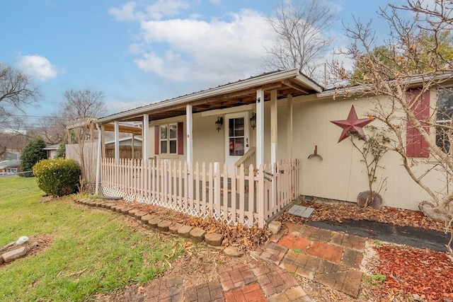 view of side of home featuring covered porch and a lawn