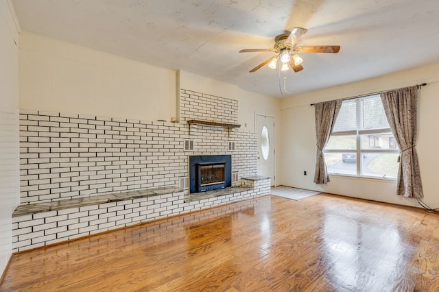 unfurnished living room with ceiling fan, a fireplace, and wood finished floors