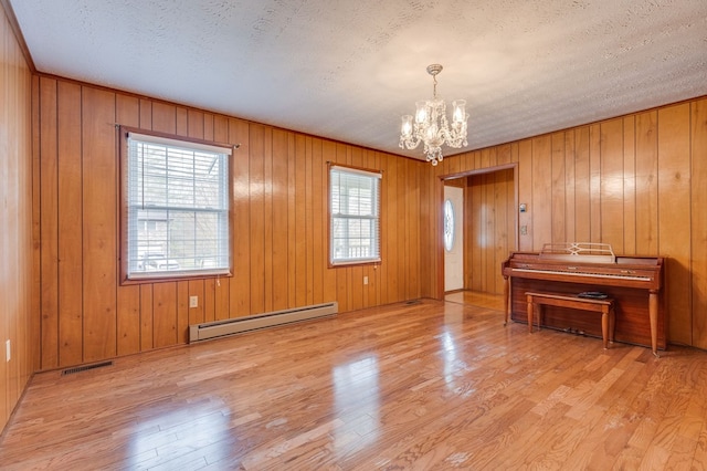 interior space with a chandelier, a baseboard radiator, wood finished floors, and visible vents