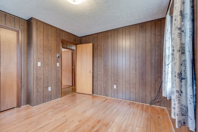 empty room featuring a textured ceiling, hardwood / wood-style floors, and wood walls