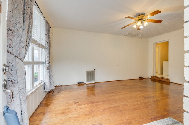 unfurnished room with ceiling fan, attic access, visible vents, and light wood-style floors