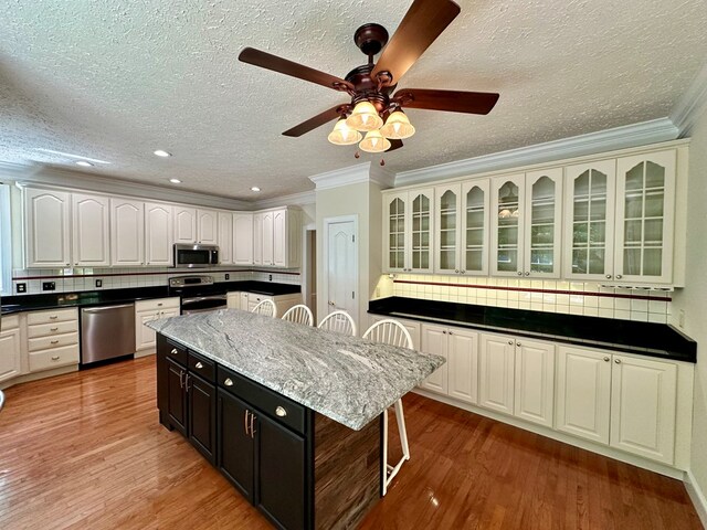 23677 Archery Range Rd, Bristol, VA 24202 - kitchen featuring appliances with stainless steel finishes, a textured ceiling, crown molding, light wood-type flooring, and a ceiling fan