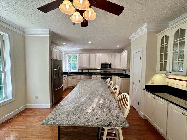 23677 Archery Range Rd, Bristol, VA 24202 - kitchen featuring appliances with stainless steel finishes, crown molding, a ceiling fan, wood finished floors, and a textured ceiling