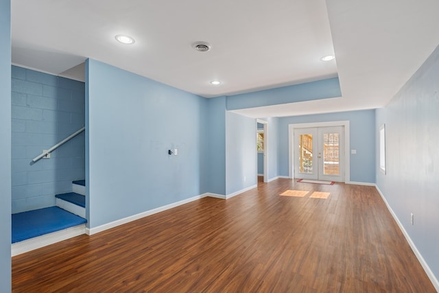unfurnished living room with baseboards, french doors, stairway, and wood finished floors