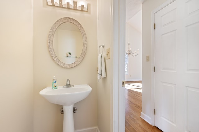 bathroom with baseboards, an inviting chandelier, and wood finished floors