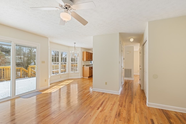 unfurnished living room with visible vents, a textured ceiling, light wood-style floors, and baseboards