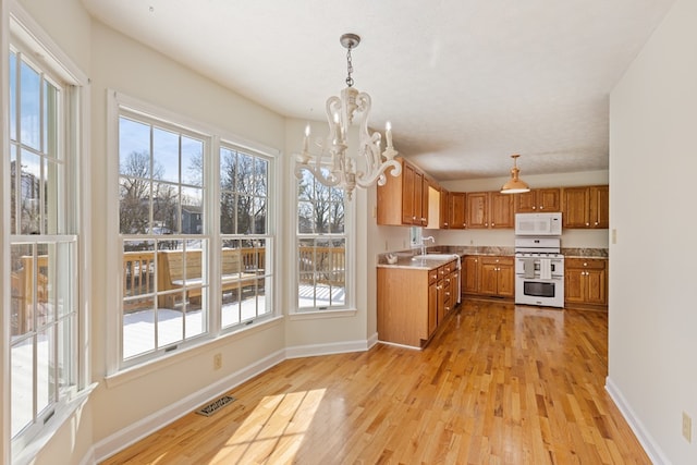 kitchen with light wood-style floors, brown cabinets, a sink, an inviting chandelier, and white appliances