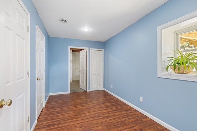 unfurnished bedroom featuring baseboards, wood finished floors, and visible vents