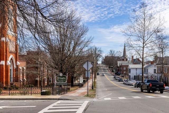 view of road featuring curbs, traffic signs, sidewalks, and a residential view