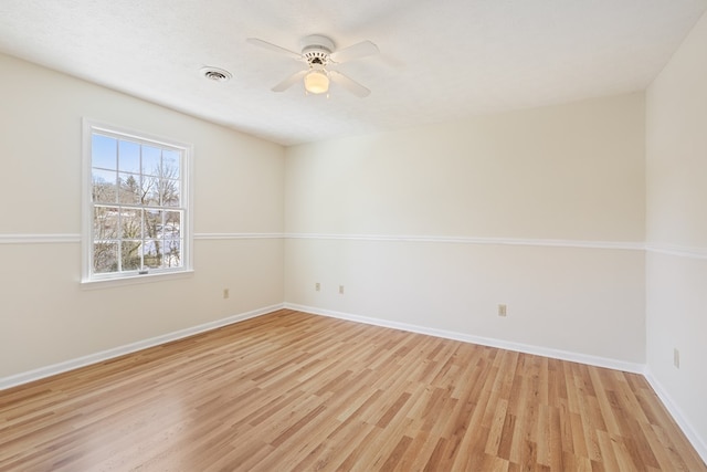 spare room with baseboards, a ceiling fan, light wood-style flooring, and visible vents