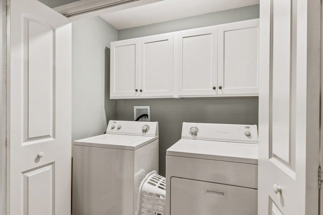 clothes washing area with cabinets and separate washer and dryer