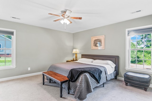 bedroom with multiple windows, light colored carpet, and ceiling fan